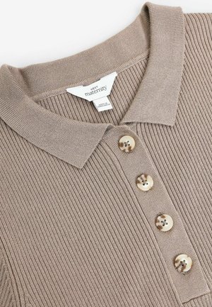 Beige soonusriided polos, millel on volditud krae ja neli dekoratiivset nuppu esiosas, valmistatud heledast plastikust.