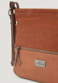 Bolso cruzado de cuero marrón con un bolsillo delantero con cremallera, una textura suave y una placa de logo metálica. Incluye una correa ajustable.