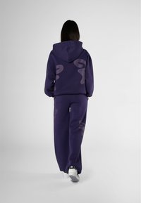 Set di felpa e pantaloni tuta viola, con un grande design a punto interrogativo sul retro. Tessuto morbido con una vestibilità comoda. Stile minimalista.