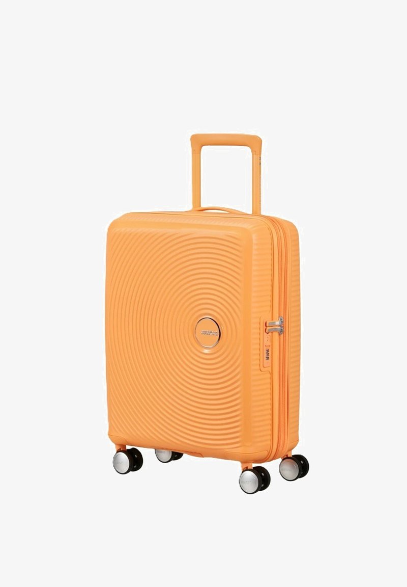 Valise rigide orange avec un design à cercles concentriques, quatre roues pivotantes, poignée télescopique et serrure à combinaison latérale.