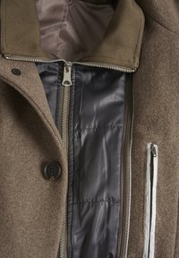 Brauner Wollmantel mit durchgehendem Reißverschluss, satinierter Innenausstattung und einer linken Brusttasche mit kontrastierendem Reißverschluss. Flache Knöpfe sind enthalten.