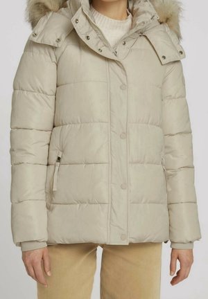 Beige quiltet vinterjakke med aftagelig hætte med pelskant, for-tryklåseknapper, lynlåslommer, båret over en hvid strikket sweater.