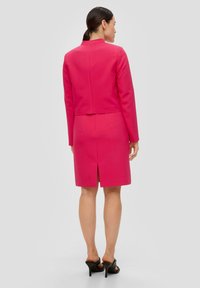 Aangesloten, cropped roze blazer en een knie-lange rok met een achterkant split. Gemaakt van een gladde stof, met strakke lijnen en een modern kraagontwerp.