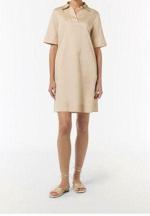 Robe beige à manches courtes avec un col, texture lisse, longueur au genou, portée avec des sandales à brides nu. Design simple sans motifs.