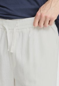 Lyse linnedragtbukser med elastisk talje og snøre, der har en blød tekstur og sidelommer.