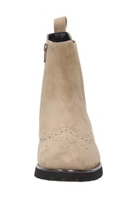 Bottine en suède beige à bout rond, avec des perforations sur le devant, une fermeture éclair sur le côté et une semelle en caoutchouc noir texturé.