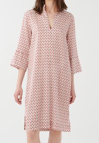 Robe à motifs avec un col en V, manches 3/4 et un ourlet au-dessus du genou. Confectionnée dans un tissu léger avec un motif répétitif rouge et vert.