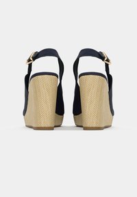 Sandalias cuña marinas con tira al tobillo, tacón de fibra natural texturizada y parte superior de tela lisa. Cuenta con un cierre de hebilla en tono dorado.