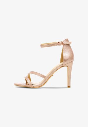 Sandalo singolo con tacco alto color oro rosa, cinturino alla caviglia, punta aperta e tacco sottile su sfondo bianco.