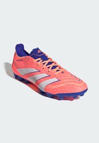Scarpa da calcio con una tomaia di un brillante rosa, decorata con texture, accenti blu e una striscia bianca. Progettata per la prestazione e l'agilità.
