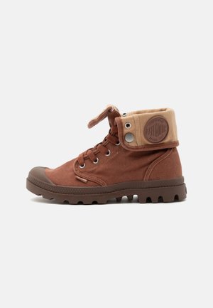 Brauner Canvas-Hochstiefel mit klappbarem beigen Kragen, Metallösen, Gummisohle und Schnürung vorne.