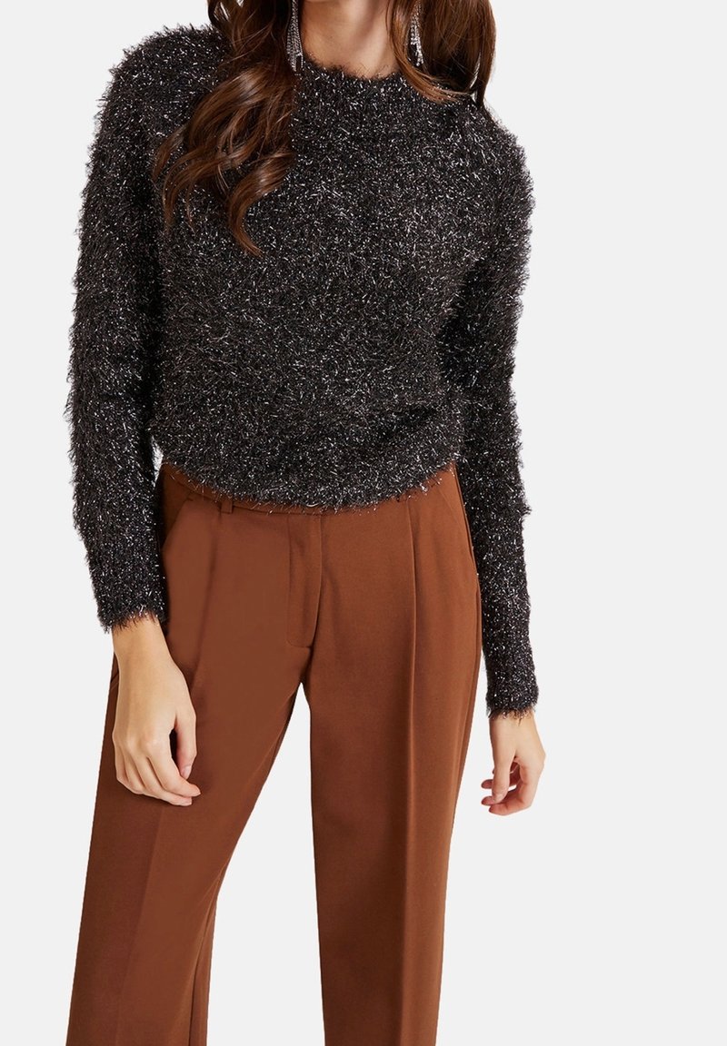 Pull en tricot noir duveteux à manches longues et col côtelé, associé à un pantalon brun taille haute ; texture douce avec une coupe ample.