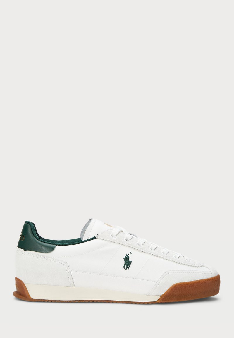 Białe trampki z zielonymi skórzanymi akcentami i brązową gumową podeszwą. Posiadają materiałową cholewkę oraz wyraźne logo po boku. Sznurowany fason.