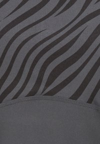 Grauer Stoff mit einem gewellten, schwarz gestreiften Muster. Glatte Textur mit einer soliden, dunkelgrauen Basis am unteren Ende. Sichtbare Nähakzente.