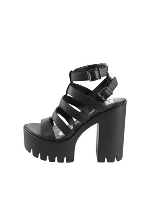 Czarna sandałka na obcasie wykonana z teksturowanego materiału, z wieloma krzyżującymi się paskami, masywną platformą i kwadratowym noskiem.