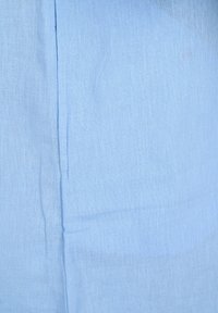 Helles blaues Gewebe mit einer weichen, strukturierten Oberfläche. Sichtbare Nähte entlang der Naht deuten auf ein gewebtes Material hin.