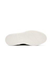 La semelle de la chaussure présente une finition en caoutchouc blanc texturé avec des rainures diagonales et horizontales pour une meilleure adhérence. Sa forme est plate avec un bout arrondi.