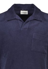 Marineblauwe poloshirt van zachte stof, met een omslagkraag, een drieknoopsluiting en een borstzak. Naaddetails zichtbaar.