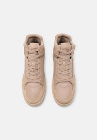 Een paar beige Tommy Hilfiger high-top sneakers met veters, details van mesh en suède, bekeken vanuit boven aan een witte achtergrond.