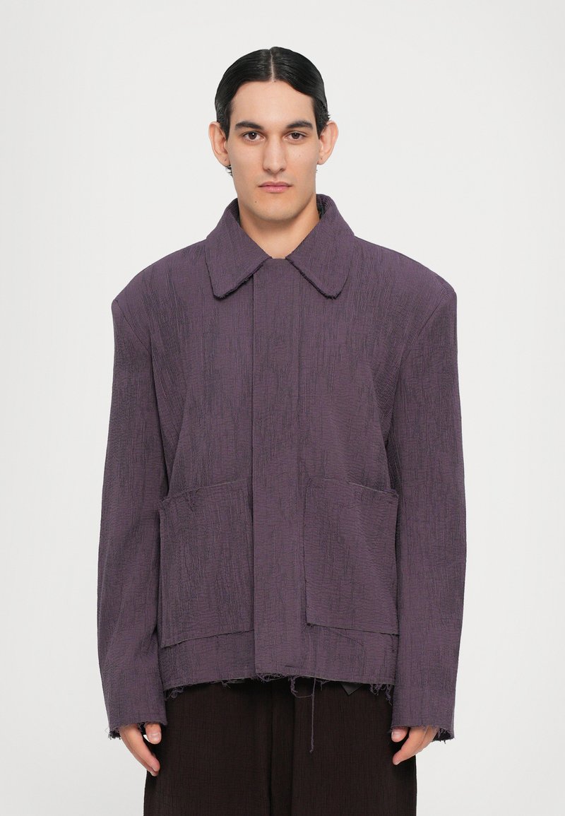 Lila texturierte Jacke mit breitem Kragen, zwei vorderen Taschen und fransigem Saum. Sie zeichnet sich durch eine lockere Passform und ein minimalistisches Design aus.