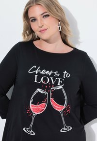 Czarna bluzka z długim rękawem z nadrukiem przedstawiającym dwie kieliszki z czerwonym winem oraz tekstem "Cheers to LOVE" w kolorze białym i czerwonym.