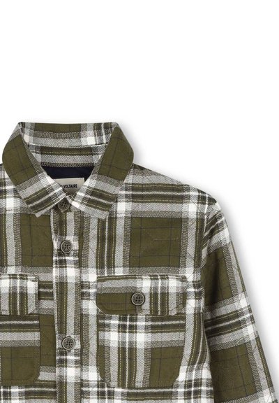 Groen en wit geruite flanellen overhemd, met een knoopsluiting bij de kraag en twee borstzakken met bruine knopen. Getextureerde katoenstof.