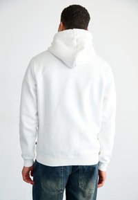 White hooded sweatshirt with a soft texture, standard fit, ribbed cuffs, and a kangaroo pocket at the front. No visible logos.
