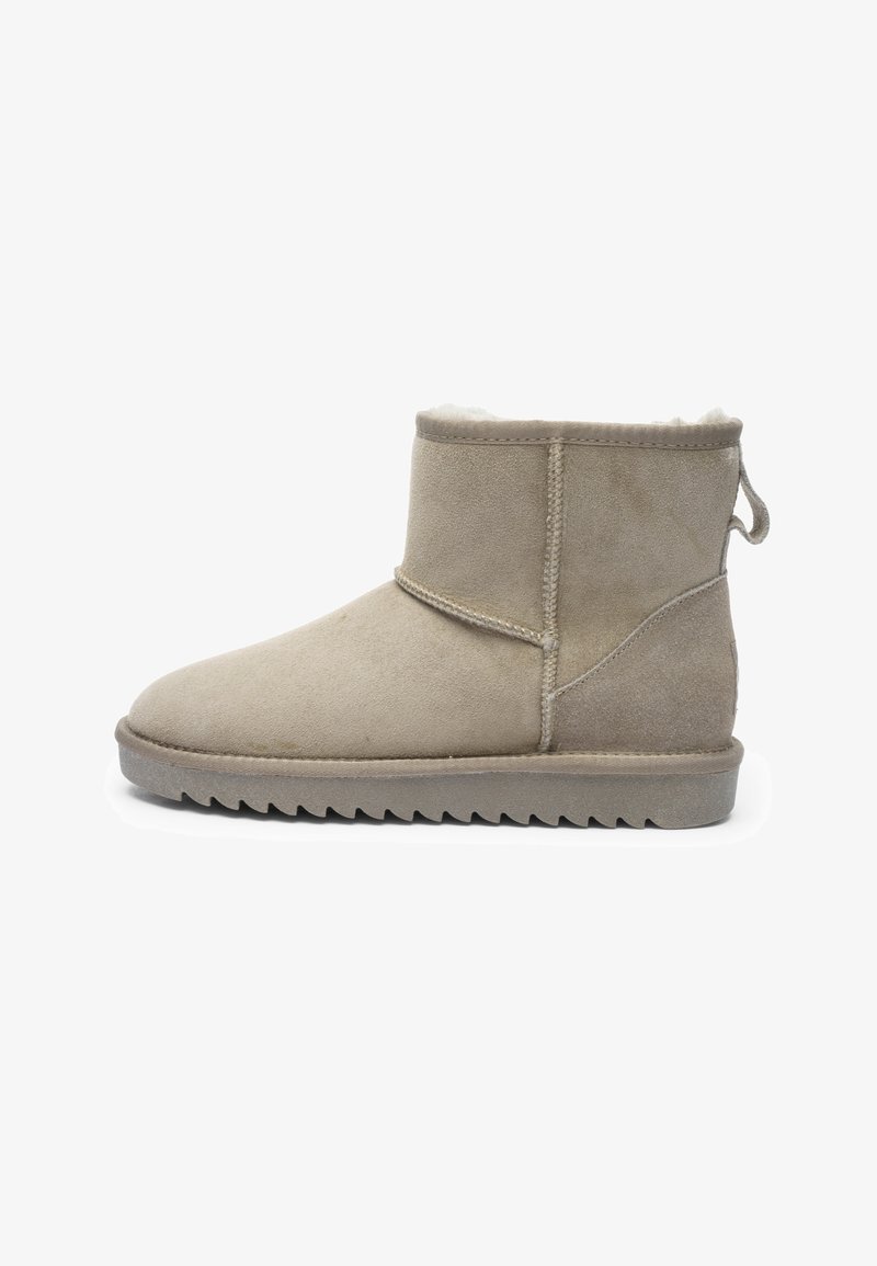 Beige suede ankle boot with a plush lining, flat rubber sole with ridges, and a pull tab at the back for easy wear.