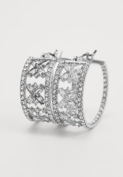 Brincos de argola prata com um design intricado, apresentando strass transparentes e um padrão de treliça, exibindo múltiplos acentos decorativos.