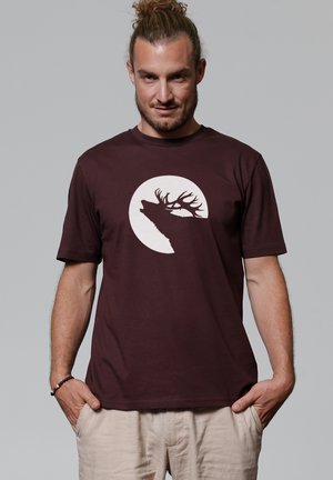 Bordeaux katoenen t-shirt met een witte silhouet van een hert tegen een cirkelvormige achtergrond. Korte mouwen en een ronde halsontwerp.