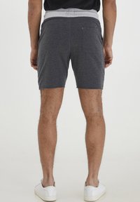 Gray cotton shorts with a light gray elastic waistband, featuring a back pocket and a casual fit, worn with white sneakers.