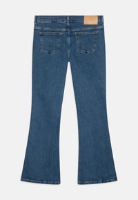 Utsvingte denimjeans i mellomblått med en jevn tekstur, med et skinnbelte og to baklommer.