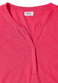 Pink short-sleeve shirt with a round neckline featuring a small V-shaped notch and a white label reading CECIL inside the collar.
