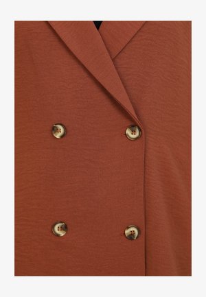 Jasnoruda podwójnie zapinana kurtka o teksturowanym wykończeniu. Posiada duże, okrągłe, zdobione guziki z przodu.