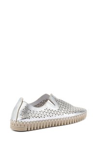 Scarpe slip-on argento con motivi ritagliati, tomaia metallica testurizzata e suola in gomma beige con scanalature verticali per una migliore aderenza.