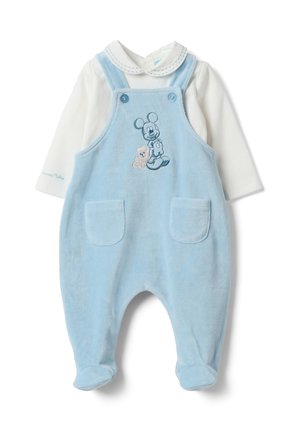 Babyblaue weiche Stofflatzhose mit Fronttaschen und Mickey-Mouse-Stickerei, getragen über einem weißen Langarmshirt mit Peter-Pan-Kragen.