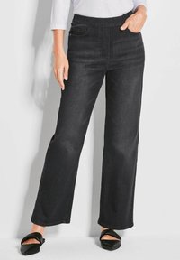 Pantalons en denim noirs à jambes larges avec une taille élastique et des poches avant. Texture lisse avec des détails de surpiqûres minimaux. Convient pour une tenue décontractée.