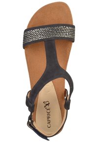 Marinblå mockasandal med en bred rem prydd med rhinestones, mjuk tan färgad vadderad sula och en justerbar vristrem.