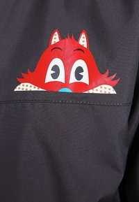 Czarna koszula z tkaniny z czerwoną twarzą zwierzęcia w kreskówkowym stylu, z dużymi oczami, białymi akcentami oraz detalami w kropki w okolicach kołnierza.