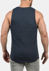 Navyblaues Tanktop aus weichem Stoff mit rundem Ausschnitt und figurbetontem Schnitt, von hinten mit minimalen Nähdetails präsentiert.