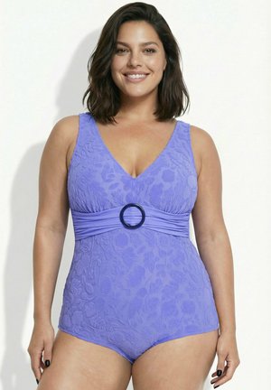 Mujer con cabello oscuro hasta los hombros, vistiendo un traje de baño entero morado con textura, escote en V y detalle de cinturón circular en la cintura.