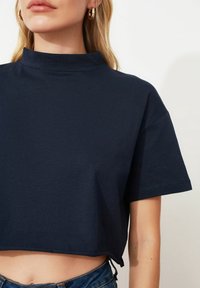 Navyblå kortärmad t-shirt med hög hals, korta ärmar och en slät textur, i kombination med blå denimjeans.