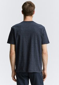 Camiseta de hombre de manga corta en azul marino oscuro con tejido texturizado y sutiles manchas de color claro, cuello redondo y corte relajado. Diseño minimalista.