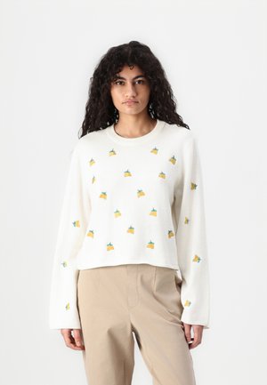 Cremfarbener, cropped Pullover mit langen Ärmeln. Verfügt über verstreute gelbe Obststickereien mit grünen Blättern. Weiche Stricktextur.