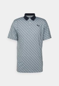 Ljusblå pikétröja med marinblå krage. Har ett all-over geometriskt mönster och en liten svart logga på bröstet. Korta ärmar.