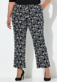 Černobílé kalhoty s paisley vzorem, elastickým pasem, rovnými nohavicemi a neformálním střihem, doplněné černými vysokými podpatky.