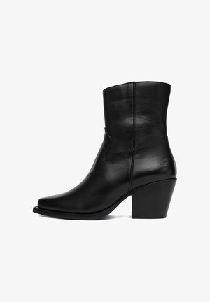 Czarny skórzany botek za kostkę z ostrym noskiem i zakrzywionym obcasem. Charakteryzuje się prostym wzorem szwów i brakiem widocznych elementów metalowych.