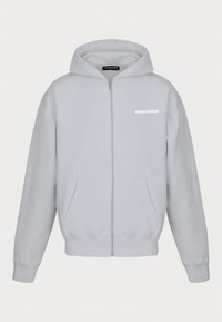 Felpa leggera grigia con zip realizzata in tessuto morbido. Presenta tasche a marsupio, polsini a coste e un logo sulla parte sinistra del petto.