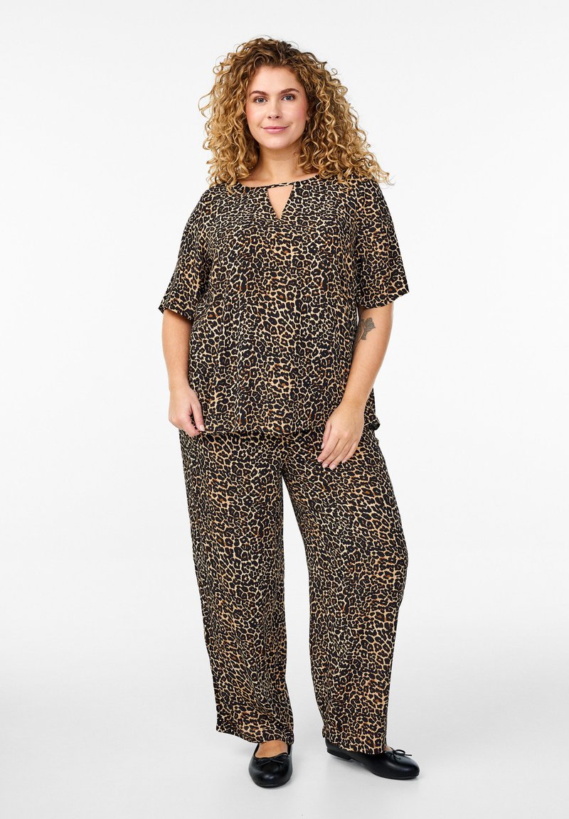 Leopardmönstrad topp med avslappnad passform och vida byxor i bruna och svarta nyanser, med korta ärmar och detalj med nyckelhål i halsen. Svarta skor.