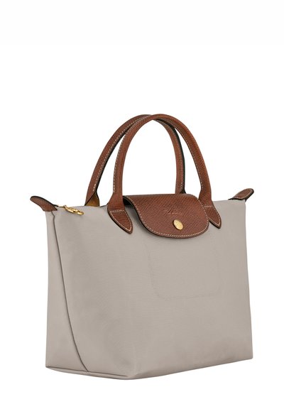 Beige fabric tote bag with brown textured leather accents, dual handles, and a flap closure featuring a gold button detail.